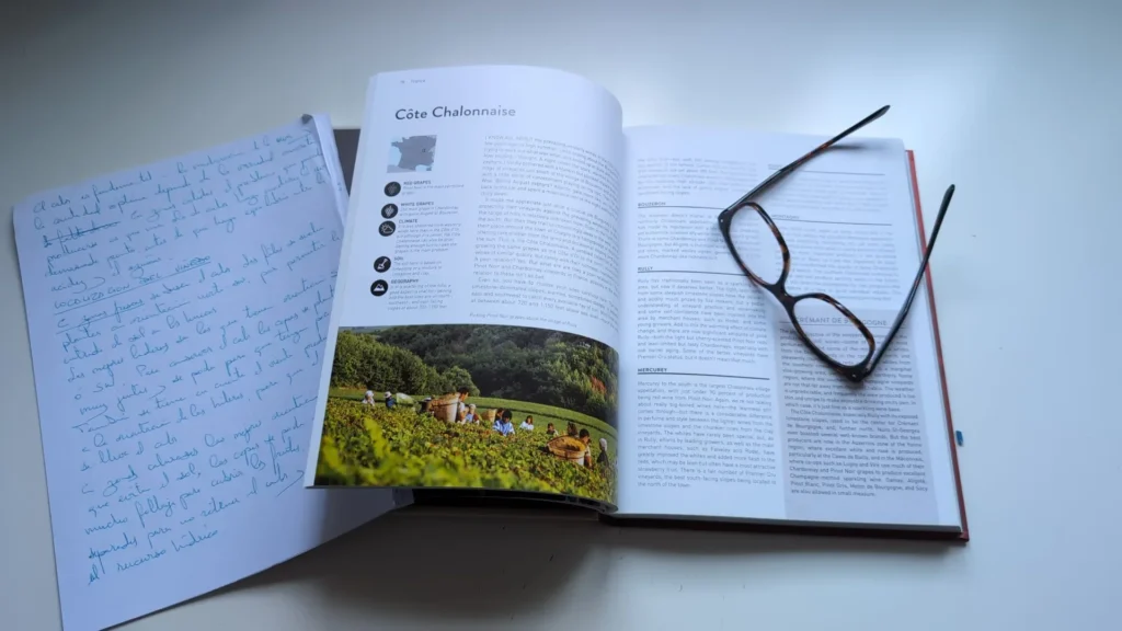 Un libro de vino abierto sobre la región de la Côte Chalonnaise en Borgoña, con unas gafas encima y una hoja con notas manuscritas al lado.