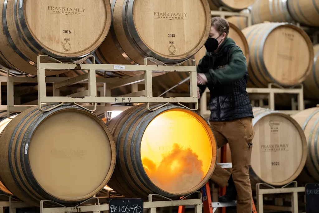 Enólogo realizando battonage en barricas de roble francés durante el proceso de crianza sobre lías