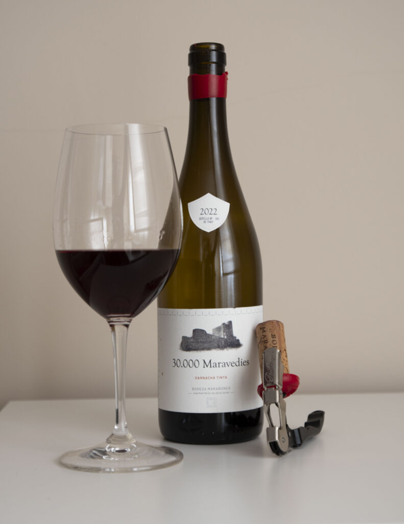 Botella de 30.000 Maravedíes 2022 de Bodega Marañones junto a copa con vino y sacacorchos sobre fondo neutro