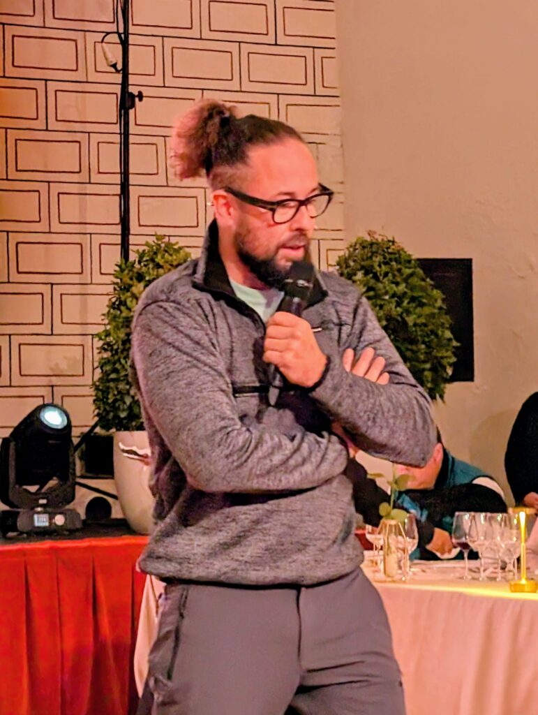 Fernando Mora, Master of Wine, con barba y el pelo recogido, dando una presentación o cata con un micrófono en la mano.