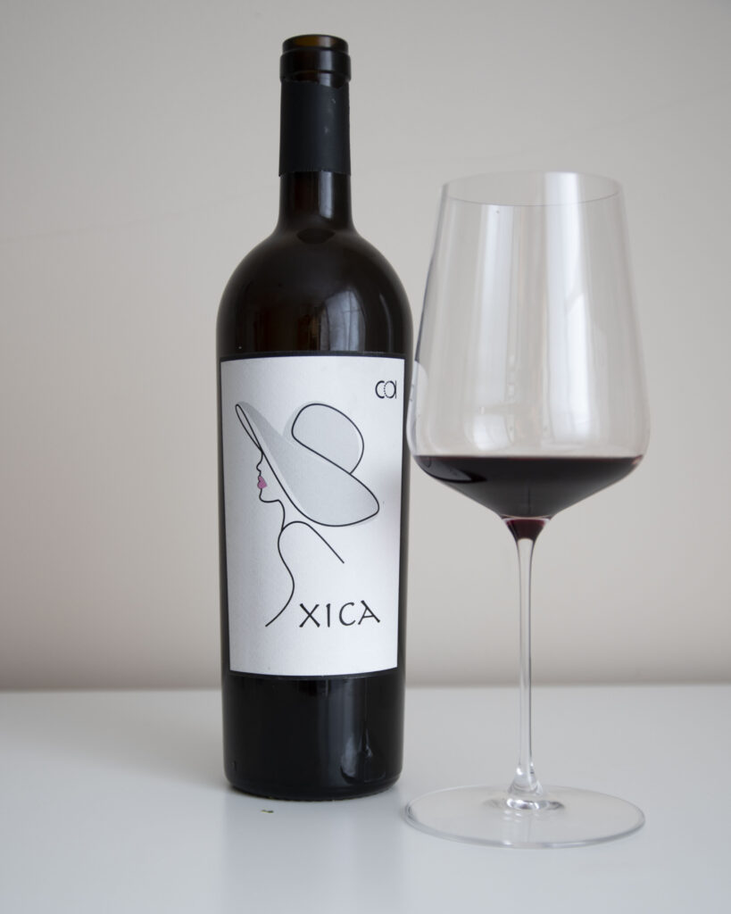 Botella de Xica 2022, con una copa servida a su lado.