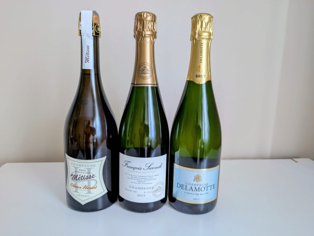 Tres botellas de espumosos de de Champagne Brut: Stéfan Hoarst (Les Riceys), François Secondé y Delamotte, alineadas sobre una mesa.