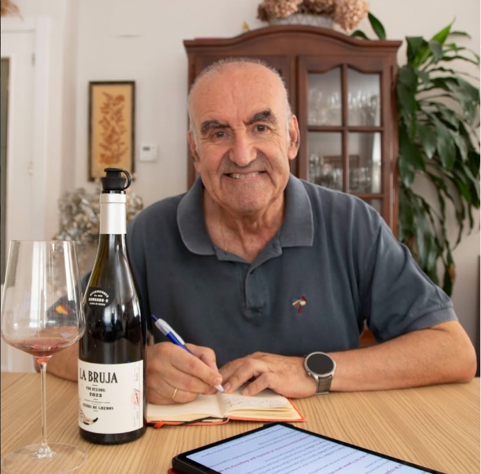Vicente Vida catando vino en casa, tomando notas en cuaderno, con copa y botella sobre la mesa