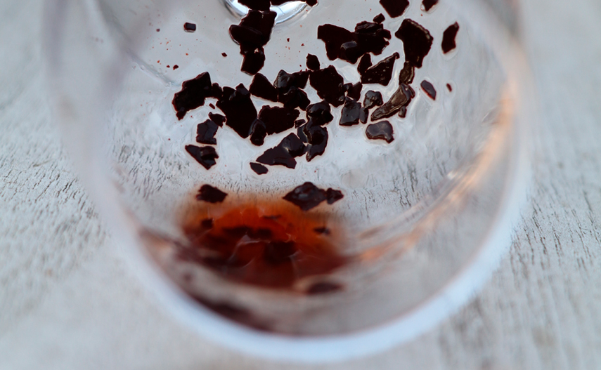 Sedimentos de vino tinto adheridos al interior de una copa transparente.