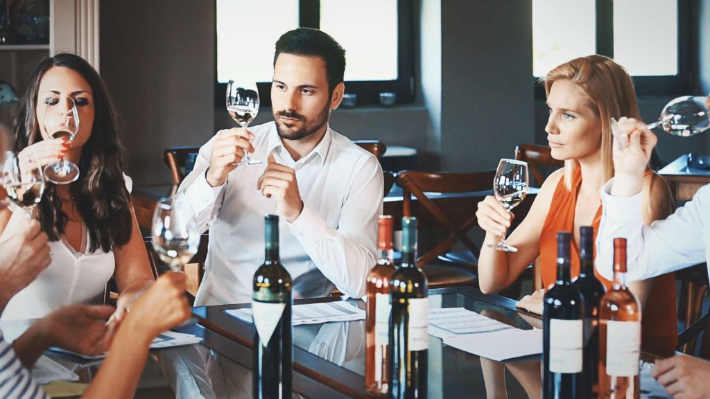 Grupo de personas catando distintos vinos y tomando notas en una mesa.
